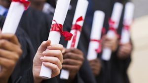 Close up of college graduates holding diplomas walking down the isle.