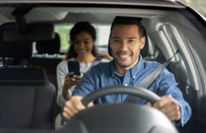 Happy driver from a car request service driving a woman and smiling - transportation concepts